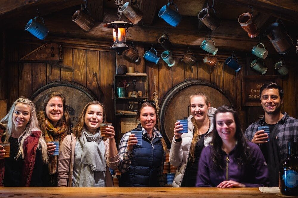 A group of young travellers having a drink in Hobbiton of New Zealand at the Green Dragon Inn during winter.