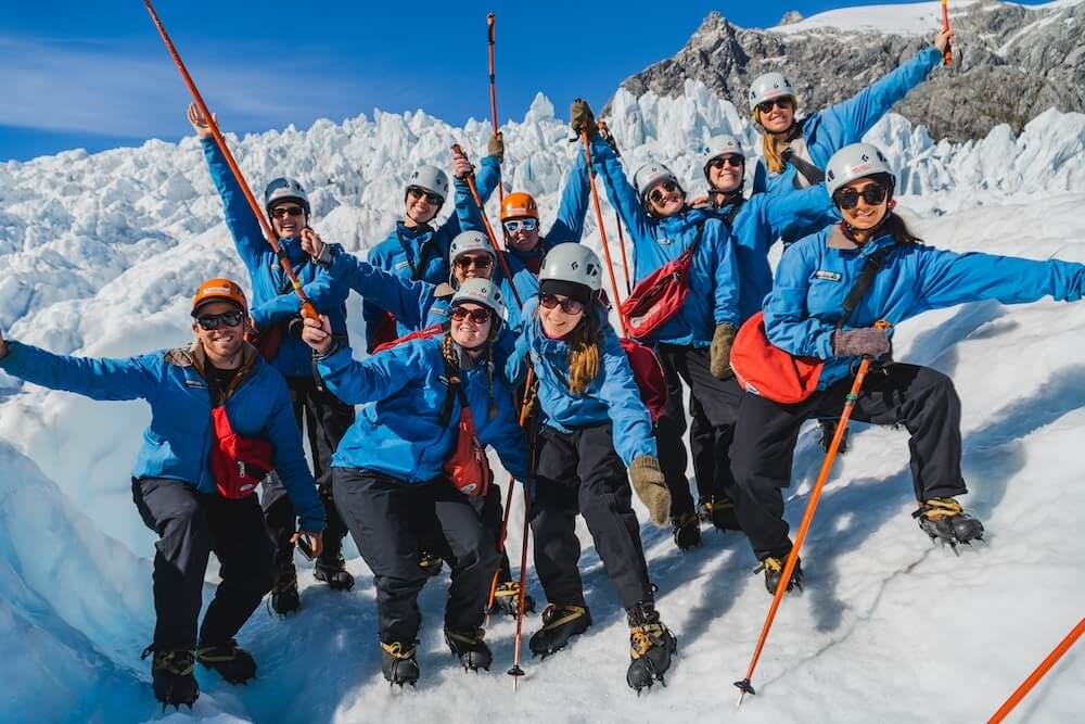 A group of young travellers on the Franz Josef heli-hike standing atop Franz Josef glacier in New Zealand.