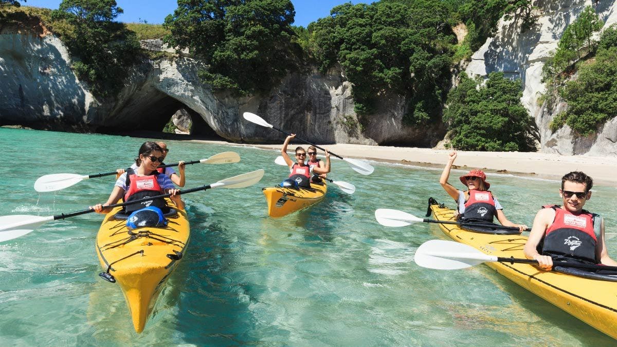 Group of people kayaking at Cathedral Cove in New Zealand