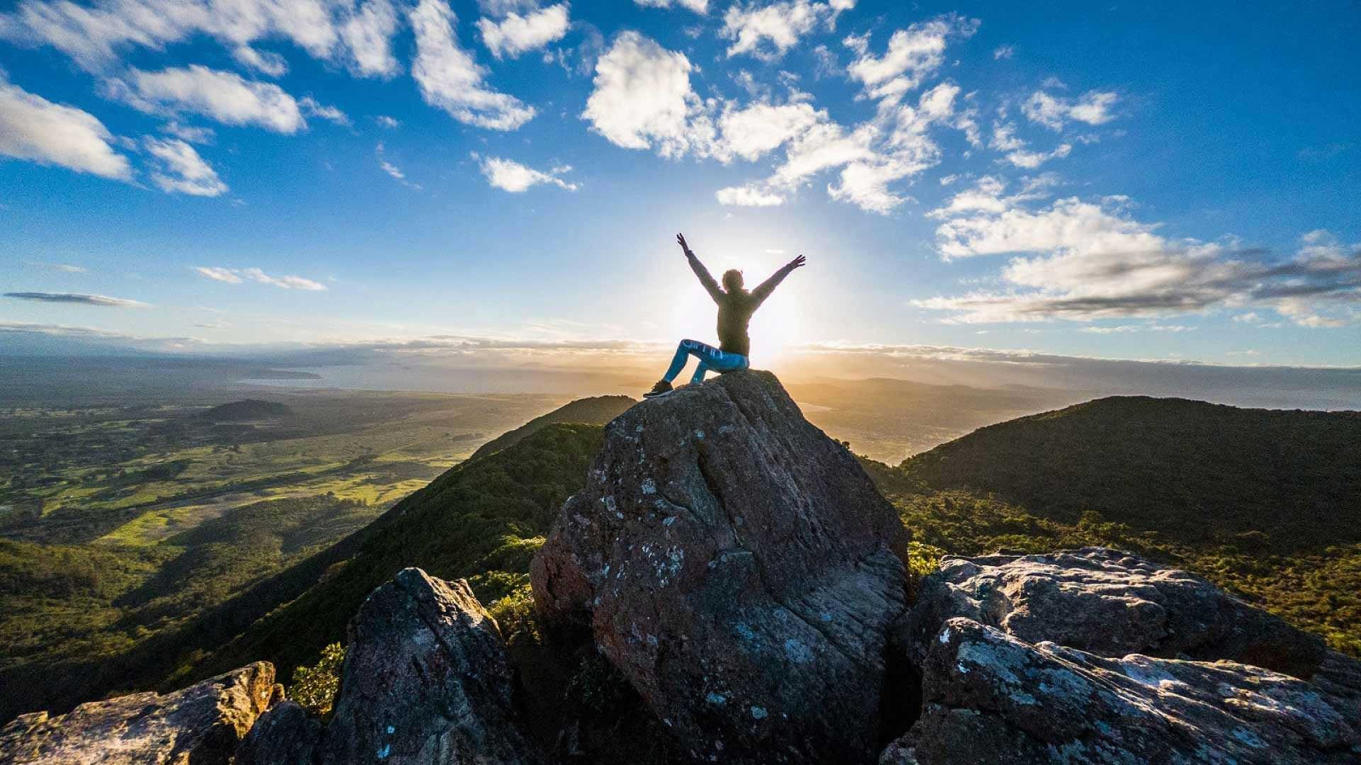 Person sitting at the top of Mount Tauhara at sunrise
