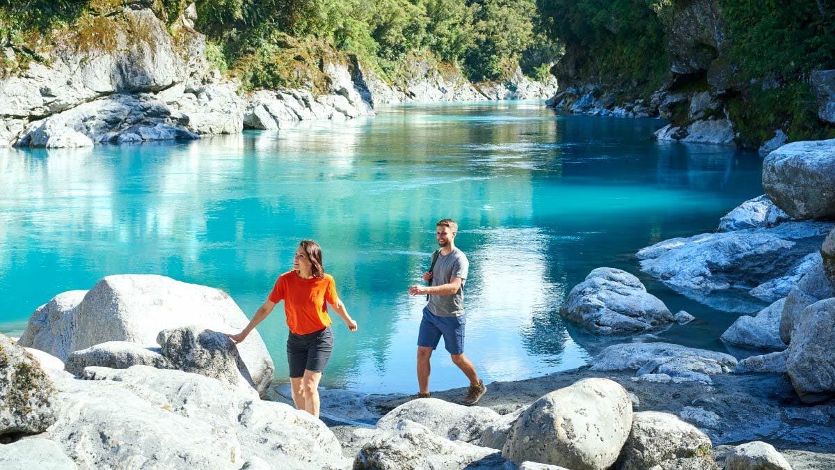 Couple walking next to a river in Haast Pass in New Zealand