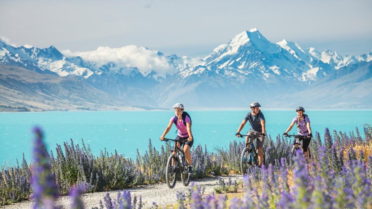 Three people cycling next to Lake Pukaki in New Zealand