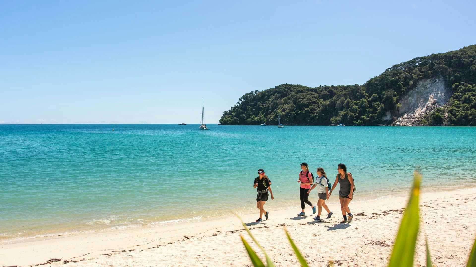 Small group of people walk the beach in Abel Tasman National Park