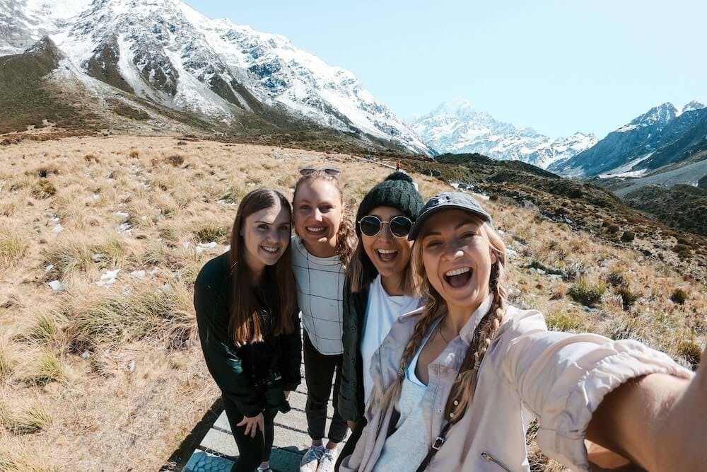 A group of four woman on a hike in New Zealand in winter with a backdrop of mountains.