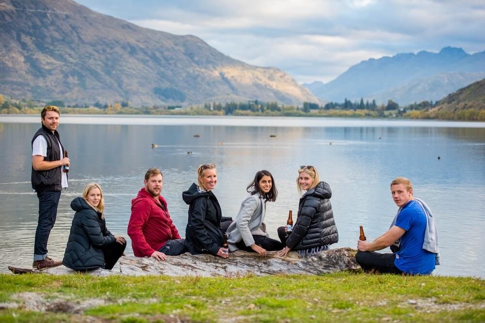 A group of people sitting lakeside wrapped in warm clothing during winter in New Zealand.