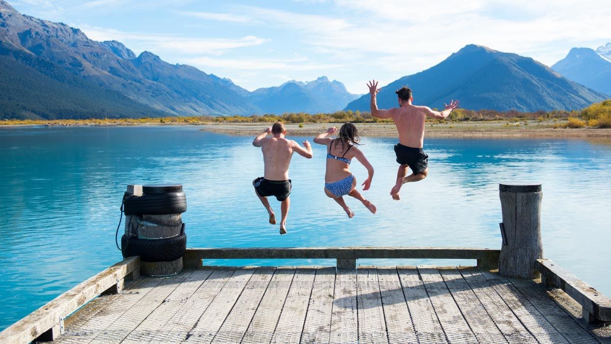 Group of friends jump off the wharf for a swim at Glenorchy in New Zealand