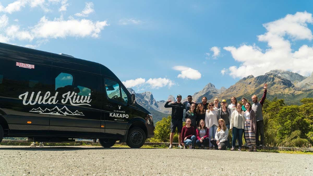 Group of Wild Kiwi Tours guests standing next to their vehicle