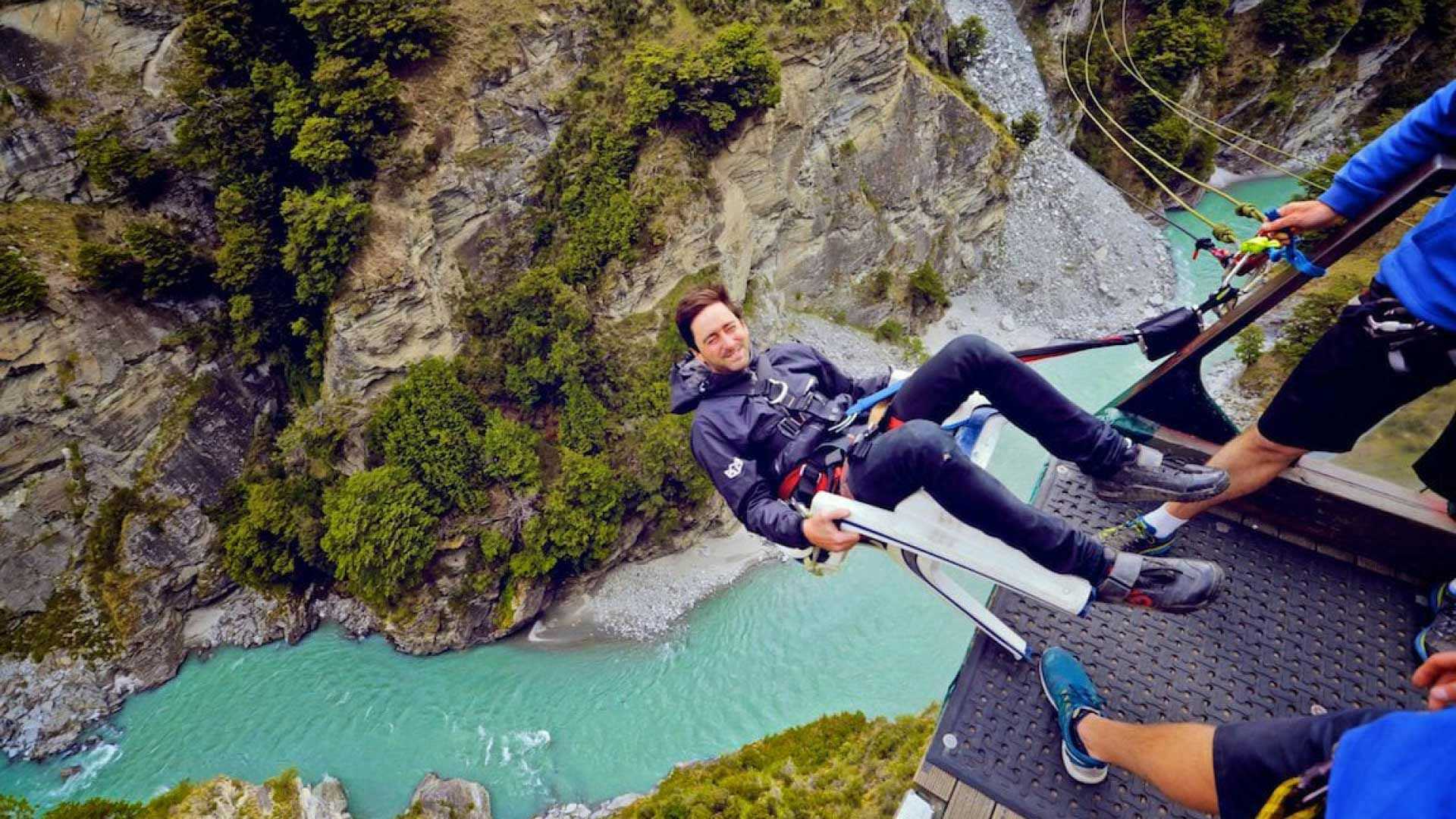 Man on a chair about to be pushed off the canyon swing