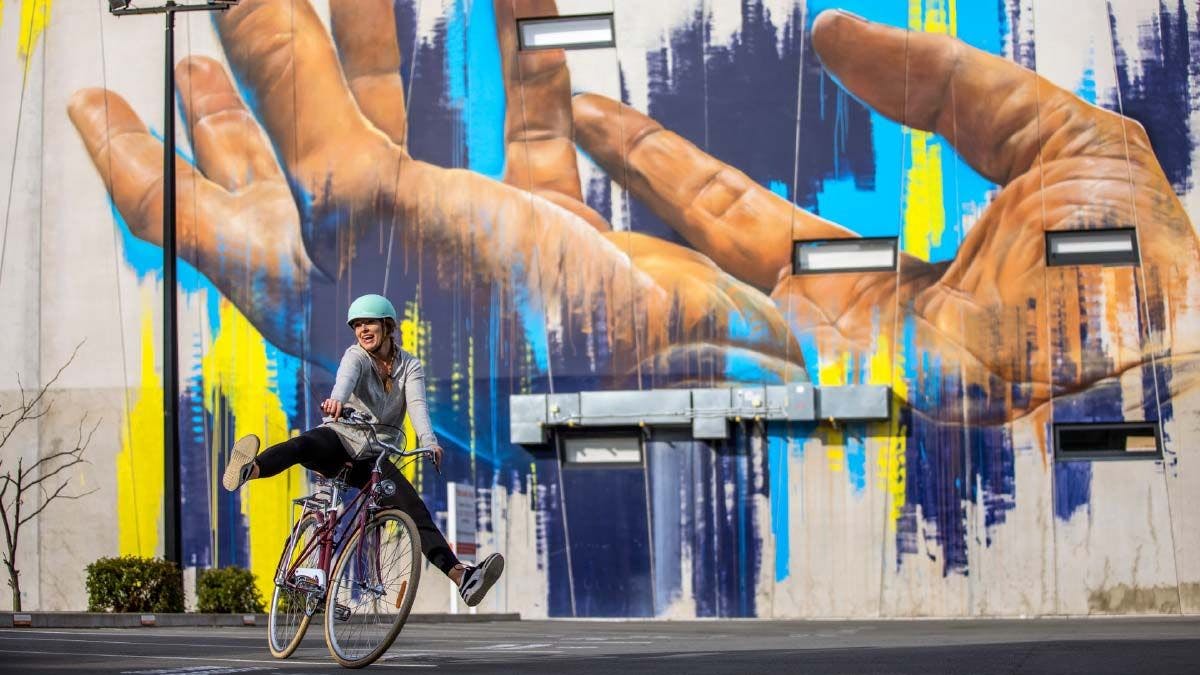 Woman on a bike in front of some street art in Christchurch