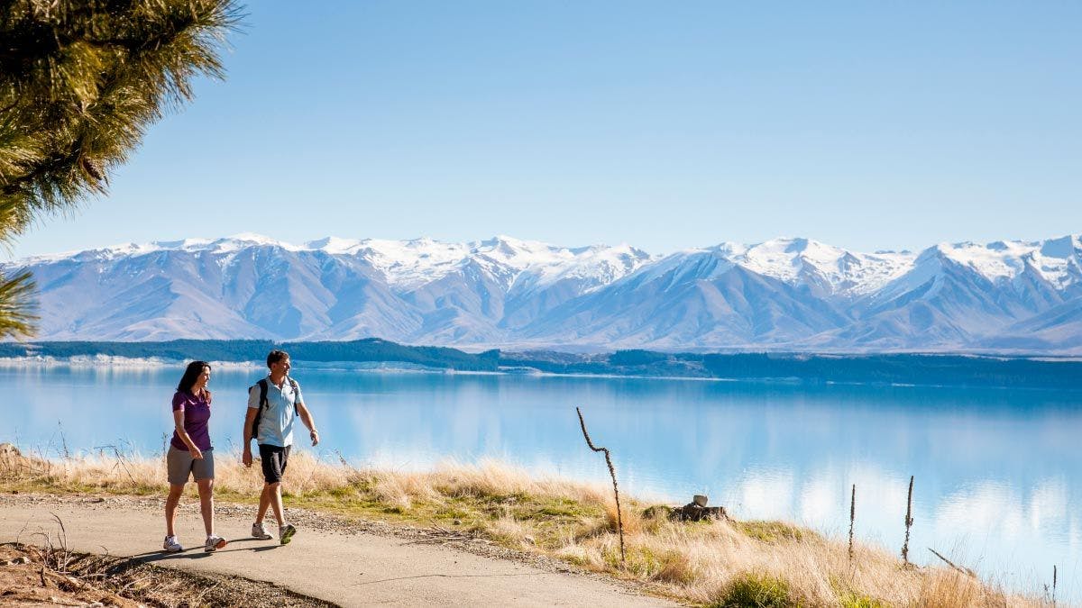 Couple walk next to Lake Pukaki in New Zealand