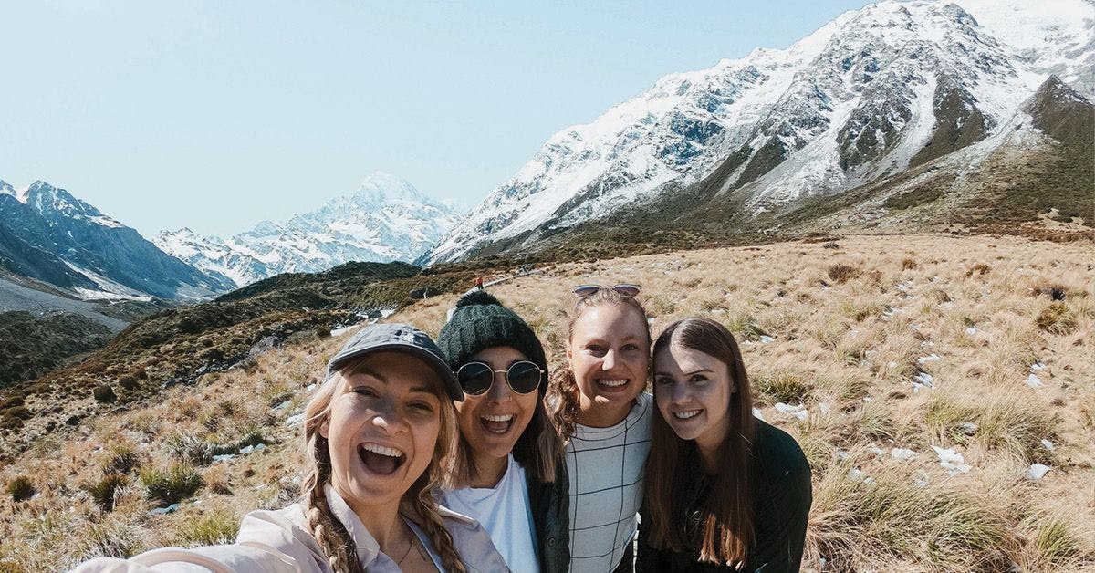 Group of people pose for a selfie front of some mountains in New Zealand