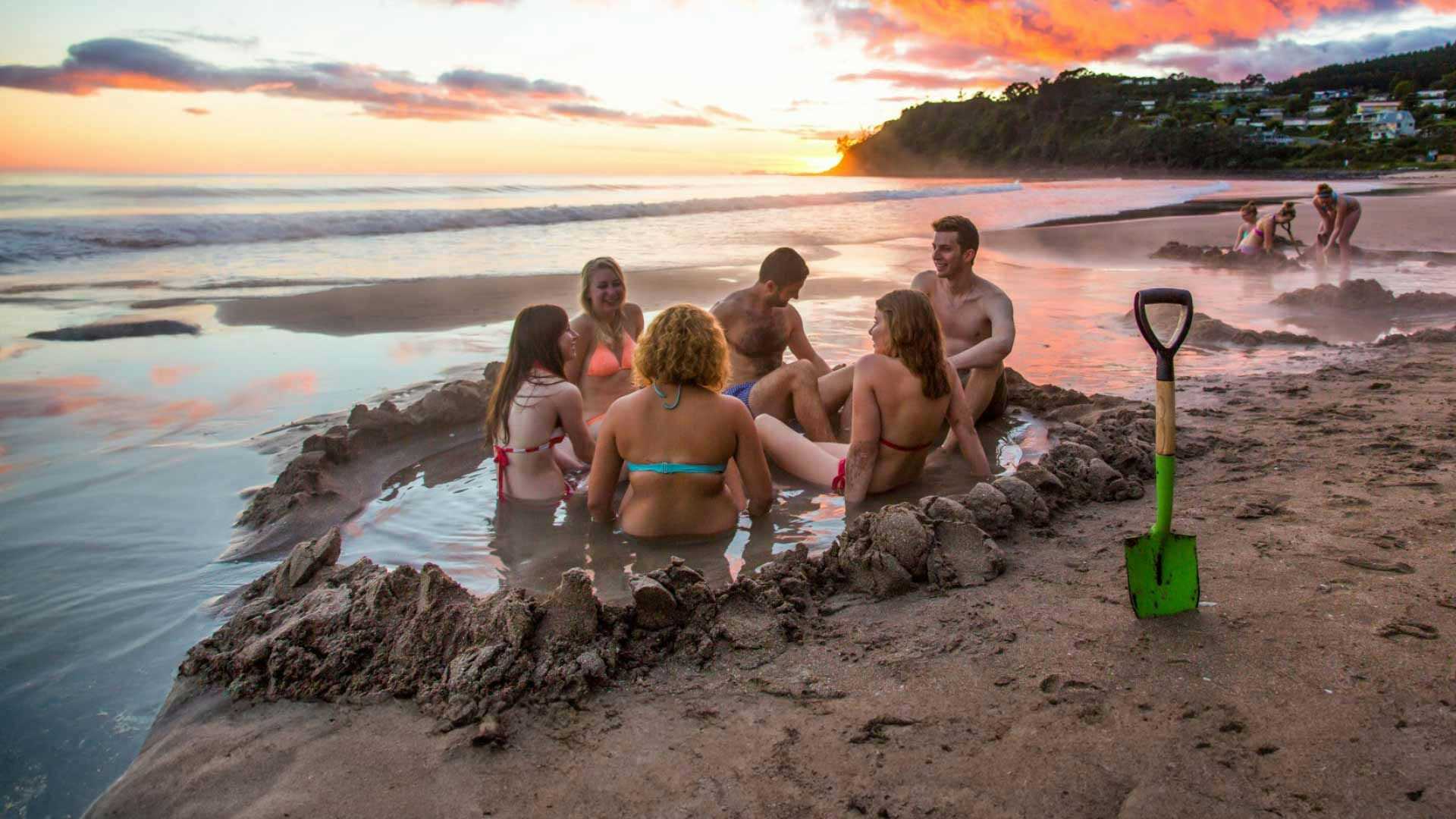 Group of people in a pool of warm water at Hot Water Beach