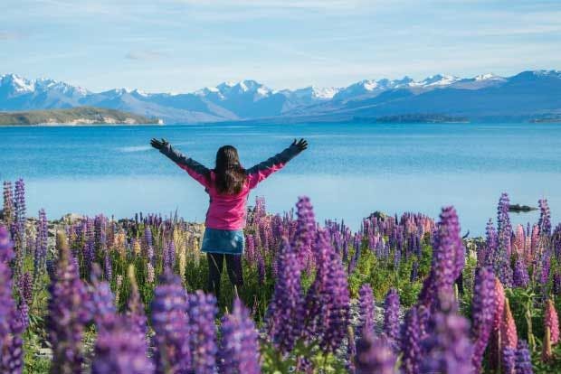 Young woman with arms viewing Lake Tekapo