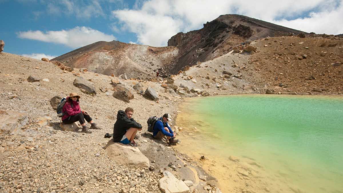 Group sitting next to an alpine lake on The Tongariro Crossing