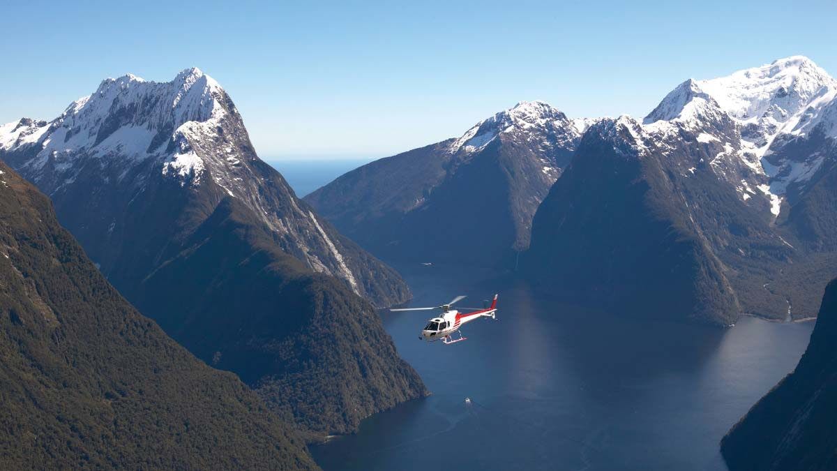 Helicopter flying through Milford Sound in New Zealand